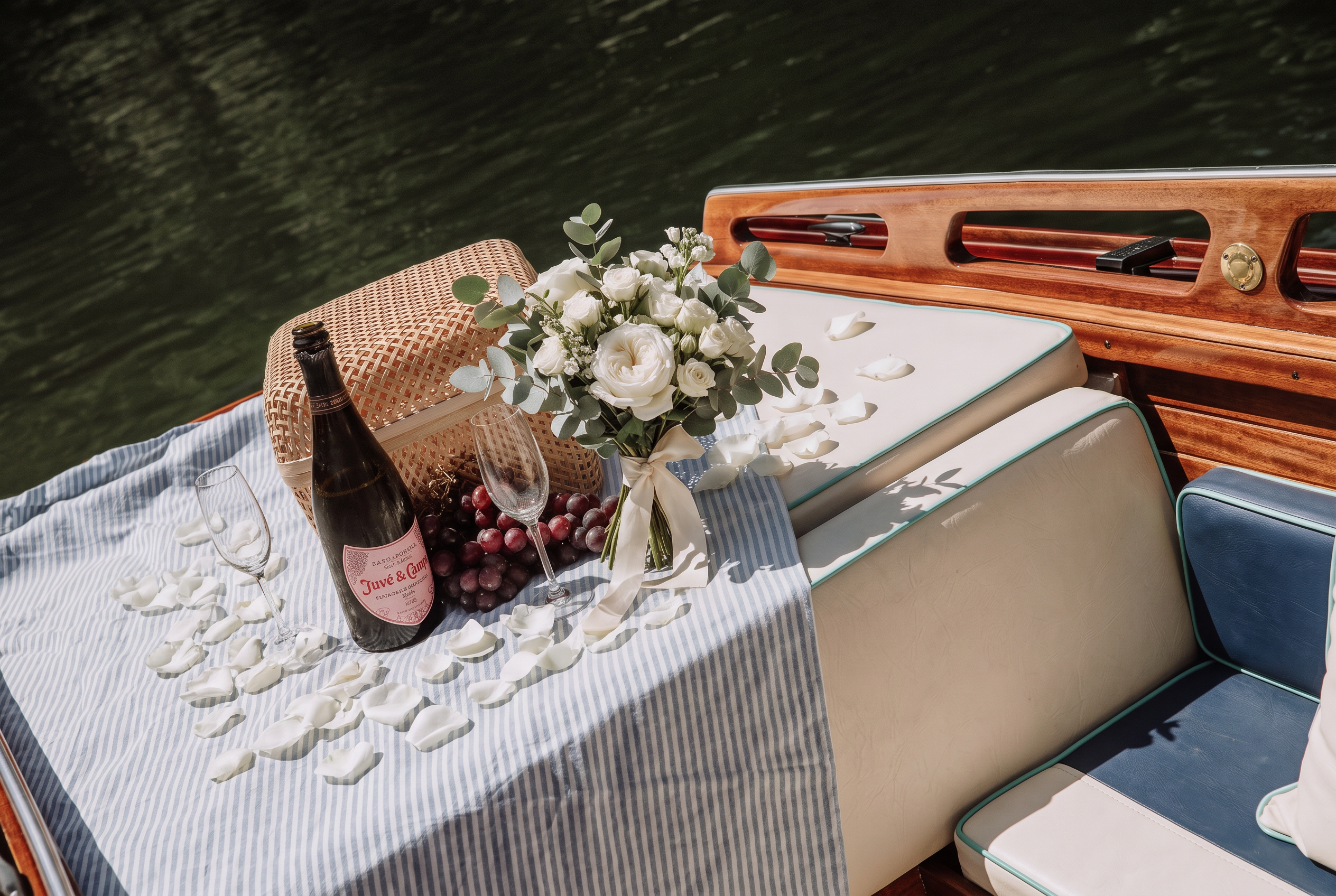 Cesto de piquenique, uvas e espumante a bordo com bouquet de rosas brancas